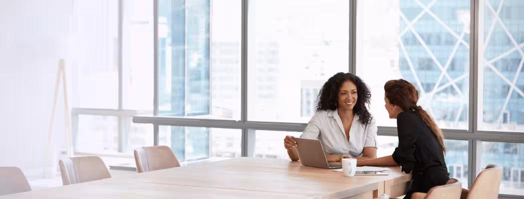 Deux collaboratrices souriantes en pleine discussion dans un bureau moderne, illustrant l’agilité et l’adaptabilité de Keiyo face au changement