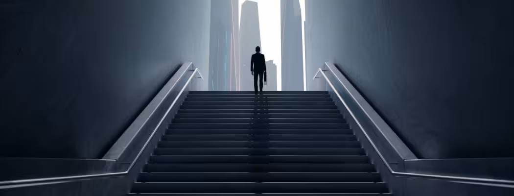 Silhouette d’un homme en costume montant un escalier vers des gratte-ciel, illustrant l’ambition et la recherche d’excellence chez Keiyo